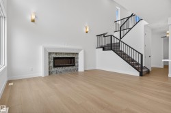 Soaring ceilings with transom windows, a linear fireplace with patterned tile surround, wood-finish flooring, and a staircase featuring black metal railings and carpeted treads - 