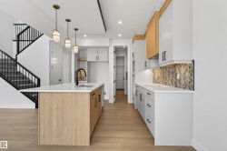 Modern kitchen featuring a light wood-finish island with a white countertop and a matte black faucet - 