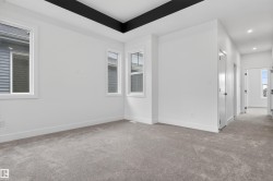Carpeted room with a black tray ceiling, multiple windows, white baseboards, and white walls - 