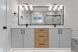 Dual vanity featuring matte gray and wood-finish cabinetry with black hardware, white countertops, and integrated sinks - 
