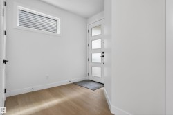 Entryway featuring a contemporary door with four frosted glass panels, wood-finish flooring, and a high-set horizontal window with blinds - 