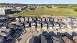 Modern suburban community featuring diverse architectural styles, concrete driveways, attached garages, and a neighborhood pond - 