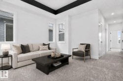 Living space featuring a coffered ceiling with dark accents, light gray carpeting, and white walls - 
