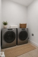 Dedicated laundry space featuring a full-size front-loading washer and dryer set, neutral wall paint, and durable flooring - 