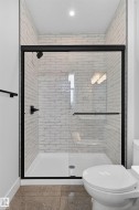 Modern shower enclosure featuring a white subway tile surround, black-framed glass door, and matte black fixtures - 