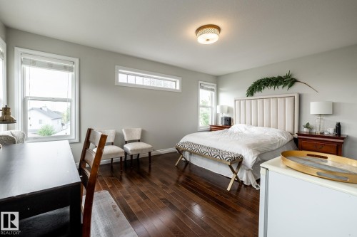 Spacious room featuring rich wood-finish flooring, light gray wall paint, and multiple windows for ample natural illumination - 2036 Towne Centre Boulevard, Edmonton, AB - Indoor Photo Showing Bedroom