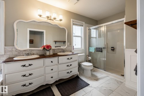 Double vanity with a wood-finish countertop, two undermount sinks, and a decorative framed mirror - 2036 Towne Centre Boulevard, Edmonton, AB - Indoor Photo Showing Bathroom