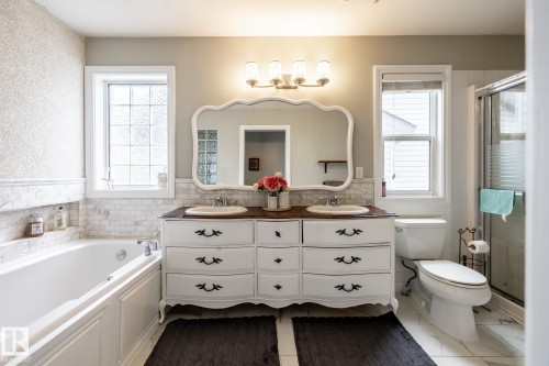 Bathroom featuring a double vanity with an ornate mirror, a built-in tub with a tile surround, a separate shower with a glass enclosure, and white tile flooring - 2036 Towne Centre Boulevard, Edmonton, AB - Indoor Photo Showing Bathroom