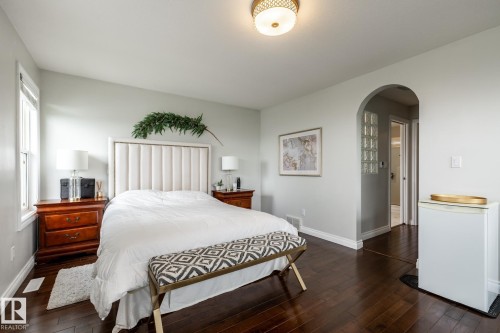 Spacious interior featuring dark wood-finish flooring, light-toned walls, and an arched doorway with glass block accents - 2036 Towne Centre Boulevard, Edmonton, AB - Indoor Photo Showing Bedroom