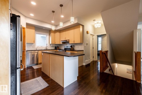 Modern kitchen featuring light wood cabinetry, a central island with dark countertops, stainless steel appliances, and dark wood-finish flooring - 2036 Towne Centre Boulevard, Edmonton, AB - Indoor Photo Showing Kitchen