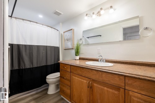 Bathroom featuring a wood-finish vanity with a built-in sink, a large mirror, and overhead track lighting - 2036 Towne Centre Boulevard, Edmonton, AB - Indoor Photo Showing Bathroom
