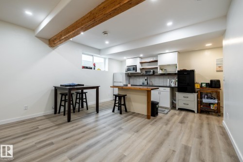 Open-concept kitchen area featuring wood-finish flooring, recessed lighting, white cabinetry, a dark countertop, and a light-colored tile backsplash - 2036 Towne Centre Boulevard, Edmonton, AB - Indoor
