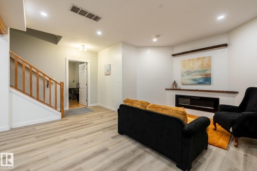 Living area featuring light wood-finish flooring, recessed lighting, and a built-in linear electric fireplace with a floating wooden mantel - 2036 Towne Centre Boulevard, Edmonton, AB - Indoor With Fireplace