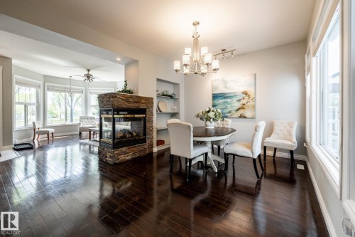 Spacious interior featuring dark wood-finish flooring, a two-sided stone-clad fireplace, and an arched entryway - 2036 Towne Centre Boulevard, Edmonton, AB - Indoor Photo Showing Dining Room With Fireplace