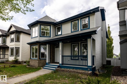 Two-story residence featuring light-colored siding with dark trim, a covered front porch with white columns and dark railings, and a prominent bay window on the upper level - 2036 Towne Centre Boulevard, Edmonton, AB - Outdoor With Deck Patio Veranda With Facade
