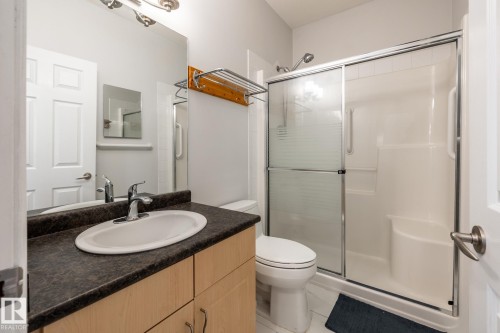 Bathroom featuring a light wood-finish vanity with an oval undermount sink, dark countertop, and a chrome faucet - 2036 Towne Centre Boulevard, Edmonton, AB - Indoor Photo Showing Bathroom
