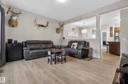 Living area featuring light wood-finish flooring, neutral wall tones, and a partial wall opening to the kitchen - 