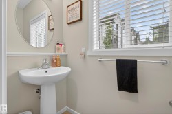 Pedestal sink with chrome faucet, circular wall mirror, and window with horizontal blinds - 