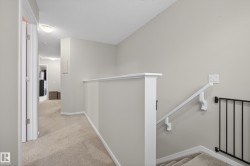 Carpeted landing with white railing and neutral wall tones - 