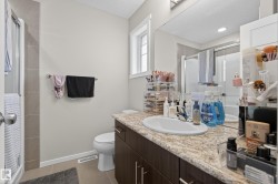Bathroom featuring a single vanity with an integrated sink, a speckled countertop, dark wood-finish cabinetry, a mirror, and a window - 