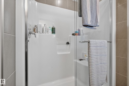 Enclosed shower with a chrome single-handle faucet, integrated shelving, and a built-in bench - 70 James Crescent, St. Albert, AB 