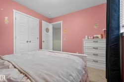 Room featuring soft pink walls, a white paneled closet door, a white dresser with black pulls, and carpeted flooring - 