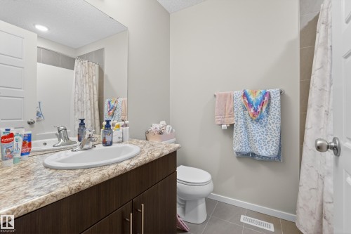 Bathroom featuring a dark wood-finish vanity with an oval undermount sink, a marble-look countertop, and a chrome faucet - 70 James Crescent, St. Albert, AB 