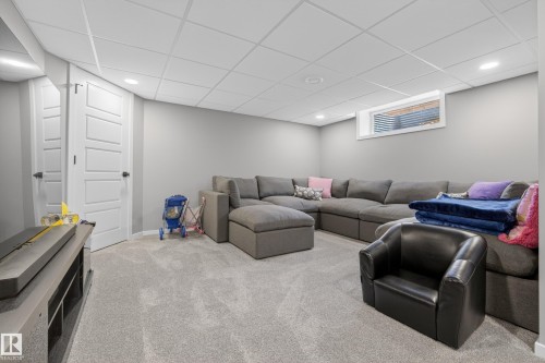 Recessed lighting illuminating a spacious carpeted area with neutral gray walls, a drop ceiling, and a single horizontal window - 70 James Crescent, St. Albert, AB 