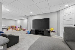 Spacious carpeted room featuring a white paneled door, flush-mounted ceiling lights, a drop ceiling, and light gray wall paint - 