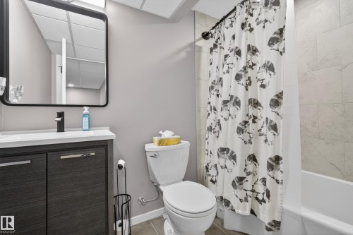 Bathroom featuring a dark wood-finish vanity with a white countertop and a black-framed mirror - 70 James Crescent, St. Albert, AB 