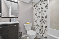 Bathroom featuring a dark wood-finish vanity with a white countertop and a black-framed mirror - 