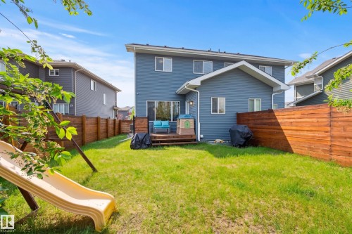 Spacious backyard featuring a wooden privacy fence, a wooden deck, and a multi-story residence with blue siding - 70 James Crescent, St. Albert, AB 