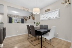 Bright dining area featuring wood-finish flooring, a contemporary drum pendant light fixture, and a large horizontal window with blinds - 