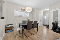 Dining area featuring wood-finish flooring, a white trim window, and a drum-style pendant light fixture - 