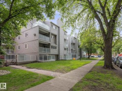Multi-story residential building featuring gray horizontal siding and individual balconies with frosted glass railings - 