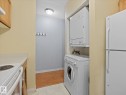Compact laundry area featuring a stacked washer and dryer - 110 10139 117 Street, Edmonton, AB 