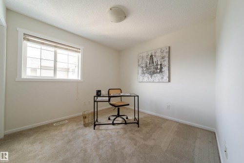 Carpeted room with a multi-pane window, neutral wall tones, and a ceiling-mounted light fixture - 405 Simmonds Way, Leduc, AB 