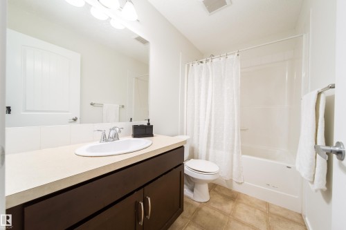 Bathroom featuring a dark wood vanity with a light-toned countertop, an integrated sink, and a chrome faucet - 405 Simmonds Way, Leduc, AB 