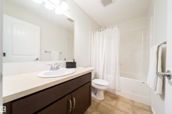 Bathroom featuring a dark wood vanity with a light-toned countertop, an integrated sink, and a chrome faucet - 