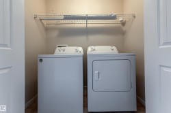 Dedicated laundry closet featuring a top-load washer, front-load dryer, and an overhead wire storage shelf - 