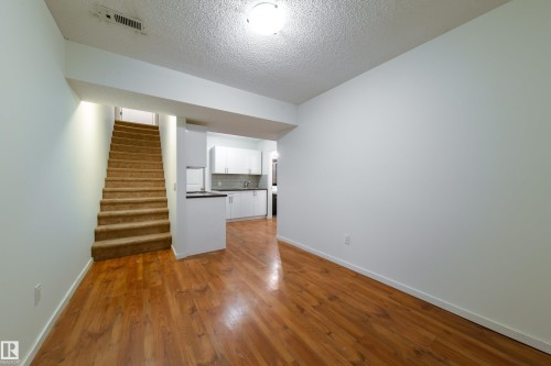 Open-concept living area with wood-finish flooring extending into the kitchen - 405 Simmonds Way, Leduc, AB 
