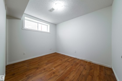 Room featuring wood-finish flooring, white painted walls, and a window with white trim - 405 Simmonds Way, Leduc, AB 
