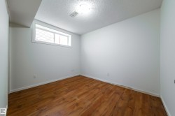 Room featuring wood-finish flooring, white painted walls, and a window with white trim - 