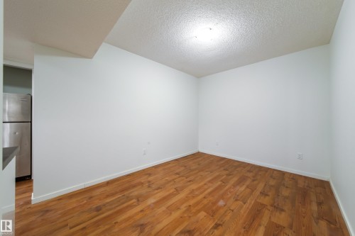 Open concept living space featuring wood-finish flooring, white baseboards, and a neutral color palette - 405 Simmonds Way, Leduc, AB 