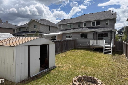 Spacious backyard featuring a built-in fire pit, privacy fencing, and a storage shed - 405 Simmonds Way, Leduc, AB 