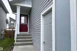 Exterior facade featuring gray horizontal siding and a prominent burgundy entryway with a transom window - 