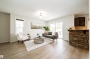 Open-concept living space featuring light wood-finish flooring, white walls, and a stone-clad kitchen island with a light-colored countertop - 405 Simmonds Way, Leduc, AB 