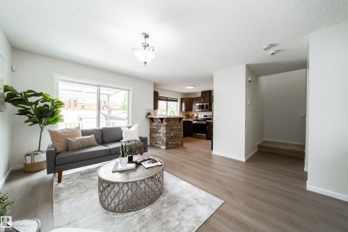 Open-concept living space featuring wood-finish flooring and a neutral color palette - 405 Simmonds Way, Leduc, AB 