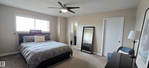 Bedroom featuring a built-in ceiling fan with integrated lighting, a large window with blinds, and neutral-toned walls - 4234 46 Street, Vegreville, AB - Indoor Photo Showing Bedroom