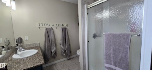Bathroom with a single vanity, a polished chrome faucet, and a stone-finish countertop - 4234 46 Street, Vegreville, AB - Indoor Photo Showing Bathroom